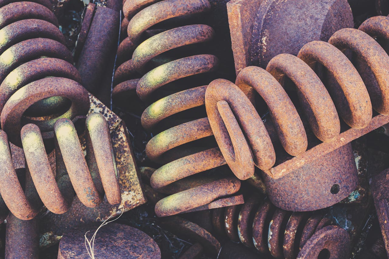 gallery-4 Detailed view of weathered and rusted metal springs in a scrapyard setting.