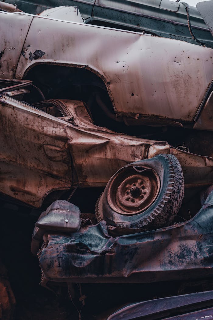 gallery-2 Close-up of rusty, damaged cars stacked in an outdoor junkyard scene.