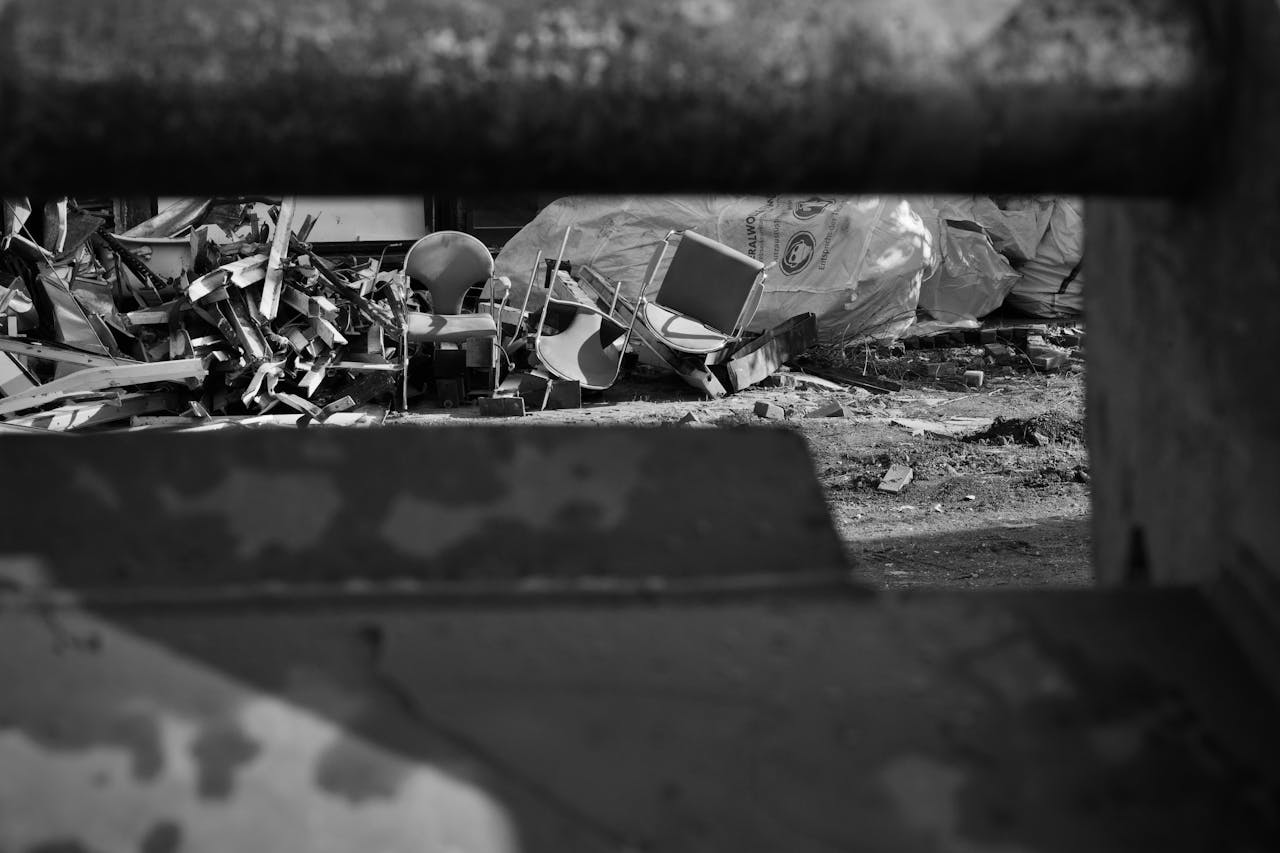 ours-journey Monochrome view of urban junkyard with scattered debris and discarded furniture.